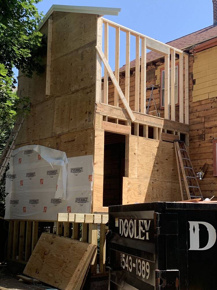 Two-story addition framing rising at the back of the house