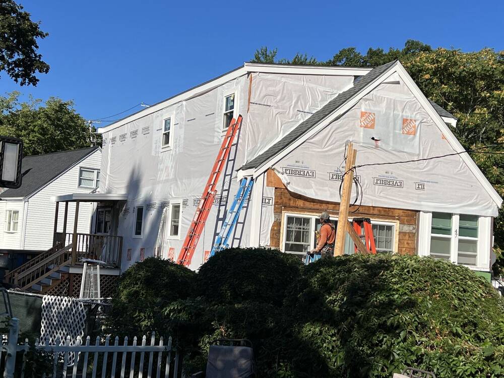 Side of the house fully wrapped with ladders in place
