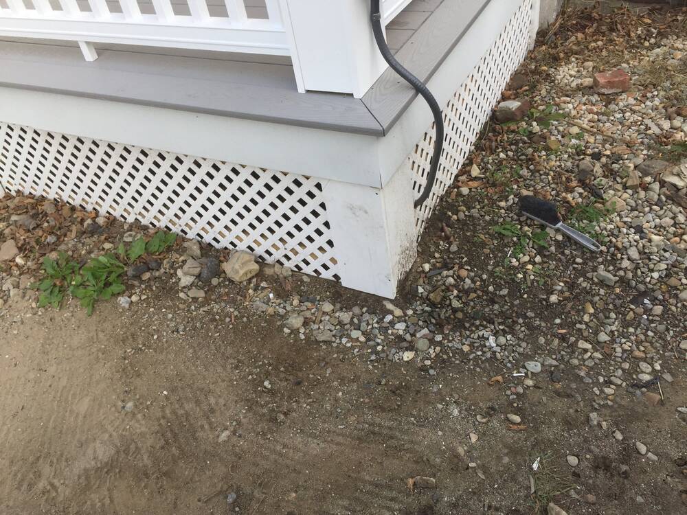 Corner detail of white trim, lattice skirting and gray composite decking