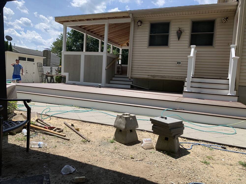 Finished covered porch and composite deck with white stair railings