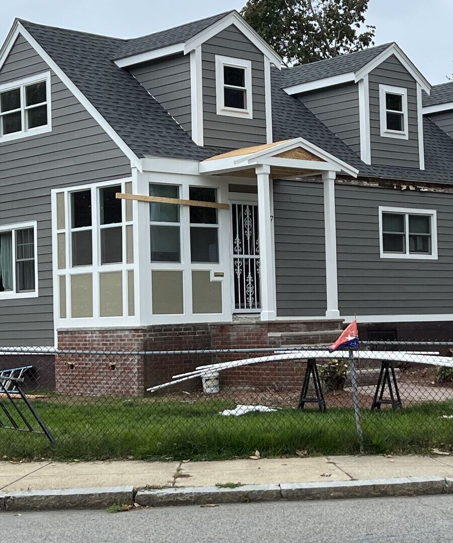 Cape-style home with new gray siding, shingle roof and dormers
