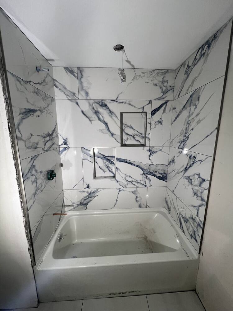 Large marble-look tile tub surround with a recessed niche
