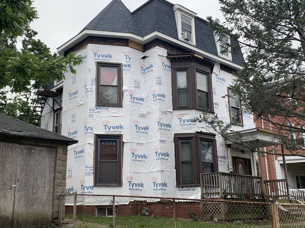 Three-story mansard Victorian wrapped in Tyvek housewrap