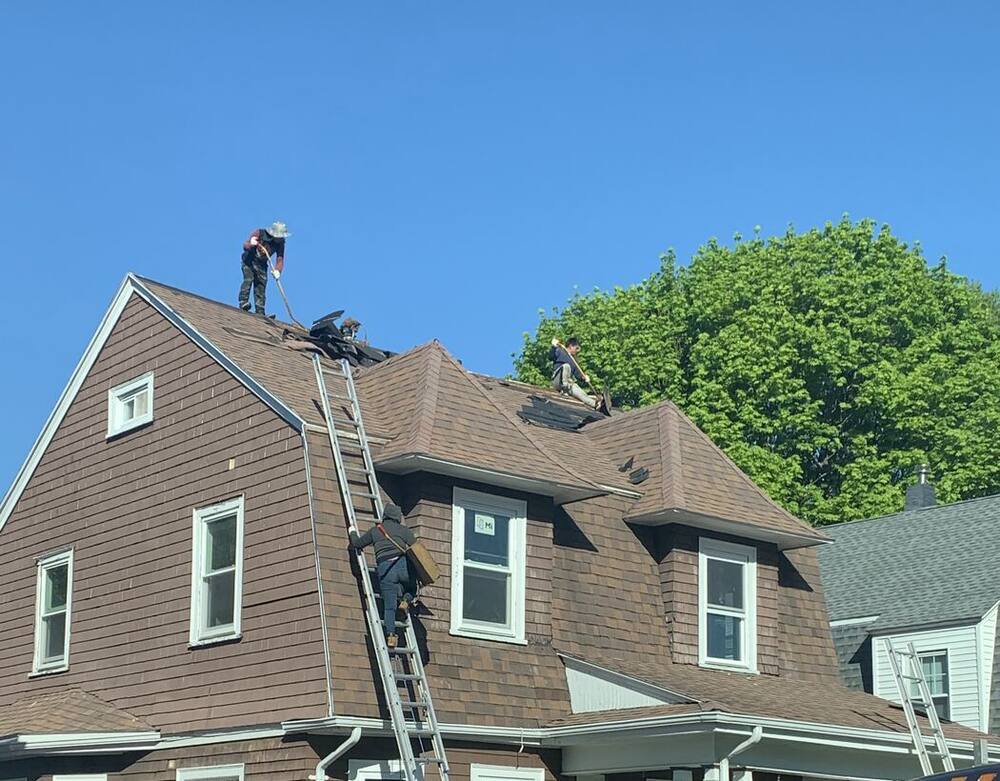 Crew stripping the old roof on a brown gambrel house